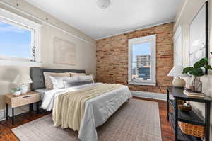 Bedroom featuring brick wall and dark hardwood / wood-style flooring