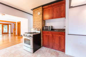 Kitchen with french doors, stainless steel appliances, ornamental molding, and light hardwood / wood-style flooring