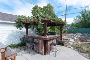 View of patio with area for grilling, a pergola, and a bar