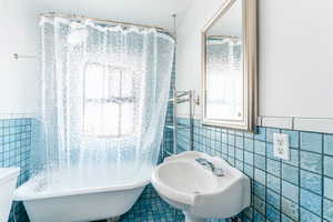 Bathroom with a bath, tile walls, sink, and tile patterned floors