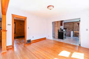 Unfurnished living room with light hardwood / wood-style flooring and brick wall