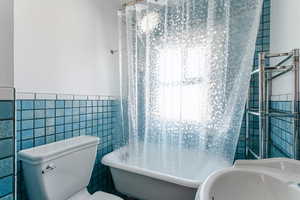 Bathroom with sink, tile walls, a bathtub, and toilet