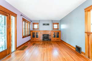 Unfurnished living room featuring light wood-type flooring, a tile fireplace, and a wood stove