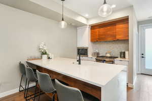 Kitchen featuring appliances with stainless steel finishes, white cabinetry, kitchen peninsula, a breakfast bar area, and pendant lighting