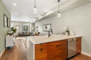 Kitchen featuring white dishwasher, light hardwood / wood-style flooring, hanging light fixtures, and sink