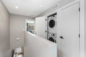 Laundry room with stacked washer and clothes dryer and light hardwood / wood-style floors