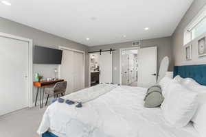 Bedroom featuring light colored carpet and a barn door