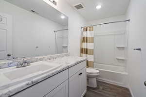 Full bathroom with wood-type flooring, vanity, toilet, and shower / bath combo with shower curtain