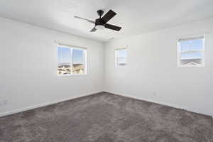 Unfurnished room featuring ceiling fan, carpet floors, plenty of natural light, and a textured ceiling