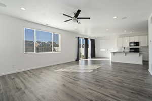 Unfurnished living room featuring a textured ceiling, sink, ceiling fan, and hardwood / wood-style flooring