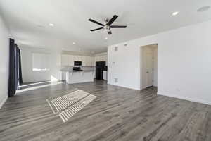 Unfurnished living room with ceiling fan, hardwood / wood-style flooring, and a textured ceiling