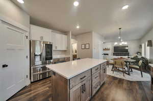 Kitchen with dark hardwood / wood-style flooring, white cabinets, a kitchen island, and stainless steel fridge