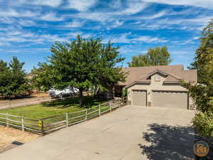 View of front of home with a spacious front yard, a 3 car garage, RV parking, and a rural view.