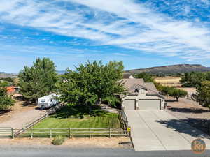 View of front of house featuring a mountain view, a front lawn, a rural view, and a garage