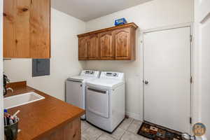 Washroom featuring cabinets, a textured ceiling, electric panel, light tile patterned floors