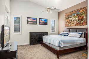 Carpeted bedroom with ceiling fan and lofted ceiling