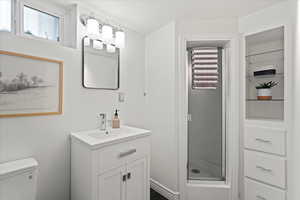 Bathroom featuring toilet, vanity, and walk in shower