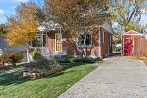 View of front of house with a front yard and a storage unit