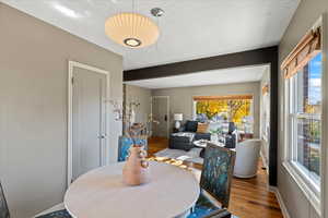 Dining room with wood-type flooring, a textured ceiling, and beam ceiling