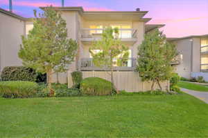 Property exterior at dusk with a lawn and a balcony