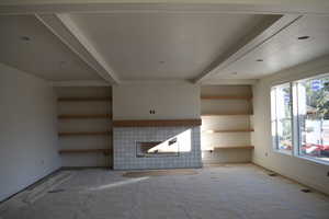 Unfurnished living room featuring a fireplace, a textured ceiling, and beam ceiling