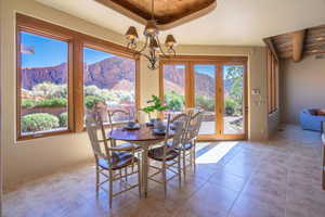 Tiled dining area featuring a mountain view, a tray ceiling, a chandelier, and french doors