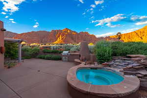 View of pool featuring an in ground hot tub, a mountain view, a grill, and a patio