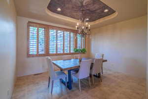 Dining room with a tray ceiling and a chandelier