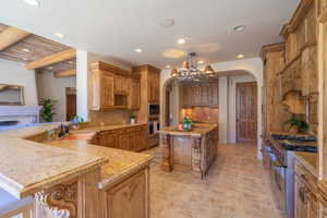 Kitchen featuring kitchen peninsula, a kitchen island, appliances with stainless steel finishes, a notable chandelier, and a kitchen bar