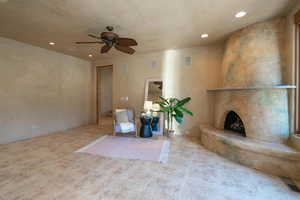 Unfurnished room featuring ceiling fan, light tile patterned flooring, and a fireplace