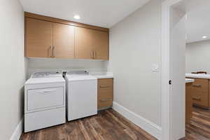 Laundry room with washing machine and dryer, dark hardwood, and cabinets