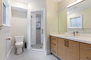 Bathroom featuring an enclosed shower, vanity, and toilet