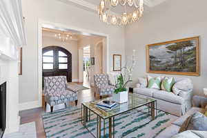 Living room with a notable chandelier, white oak floors, and crown molding