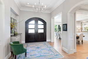 Entryway featuring white oak floors, a notable chandelier, and crown molding