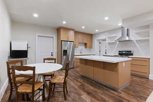 Kitchen with tasteful backsplash, a kitchen island, wall chimney range hood, stainless steel appliances, and dark hardwood  floors