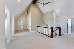 Hallway featuring light carpet, beamed ceiling, and high vaulted ceiling