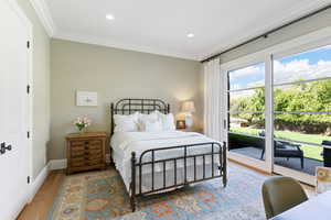 Bedroom featuring white oak floors, crown molding, and access to exterior