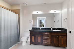 Bathroom featuring tile patterned floors, a shower with curtain, vanity, and toilet