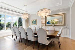 Dining room with crown molding, white oak floors, a tray ceiling, and a chandelier