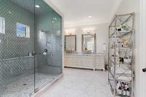 Bathroom with ornamental molding, vanity, and a shower with door