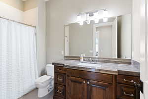 Bathroom with curtained shower, vanity, toilet, and tile patterned floors