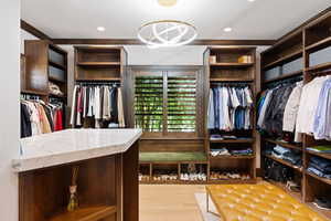 Spacious closet with an inviting chandelier and white oak floors