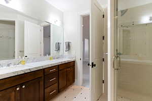 Bathroom featuring tile patterned flooring, a shower with door, and vanity