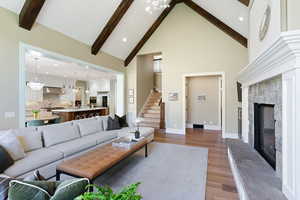 Living room featuring a fireplace, white oak floors, a chandelier, and high vaulted ceiling