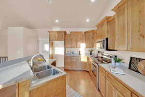 Kitchen featuring sink, stainless steel appliances, light brown cabinets, and light hardwood / wood-style flooring