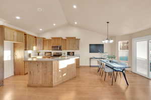 Kitchen featuring appliances with stainless steel finishes, light wood-type flooring, vaulted ceiling, light brown cabinets, and a chandelier