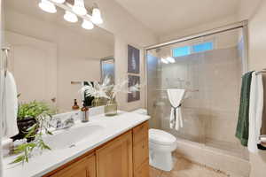 Bathroom with tile patterned flooring, vanity, toilet, and a shower with door