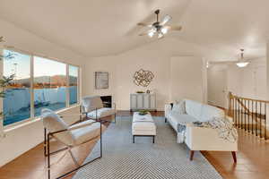 Living room with ceiling fan, light hardwood / wood-style flooring, a water view, and vaulted ceiling