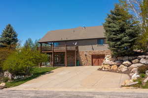 View of front facade with a wooden deck and lower level 4th car garage, a lot of parking.