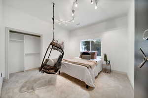 Bedroom with light colored carpet and a closet